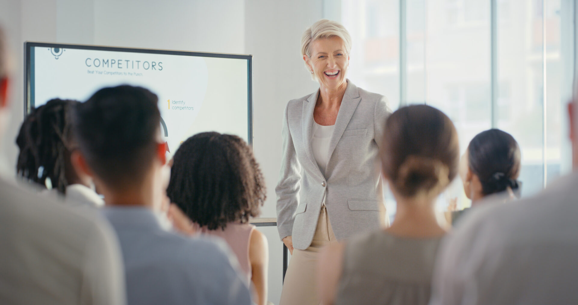 Female leader, manager or CEO giving a presentation in a workshop or seminar for training, learning and coaching at work. Mature business woman talking to an audience and laughing during a conference